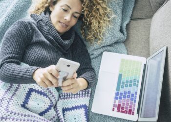 curly woman with gray sweater lying on brown sofa