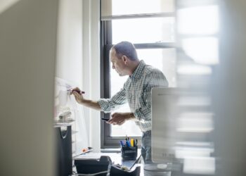 office life a man standing up working and making notes on a wall chart project management