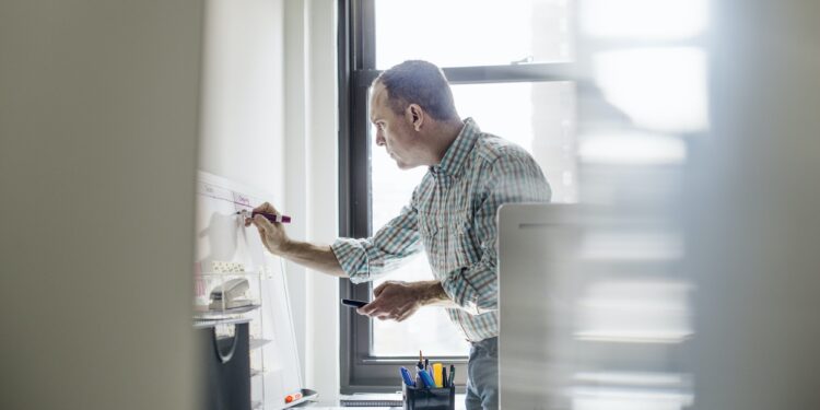 office life a man standing up working and making notes on a wall chart project management