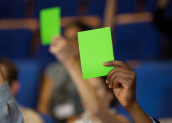 Business executives show their approval by raising hands at conference center